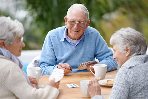 Senior assisted living residents playing a card game and smiling.
