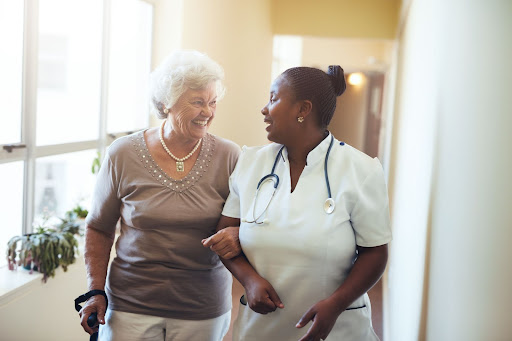 Medical care staff walking with smiling senior assisted living resident.